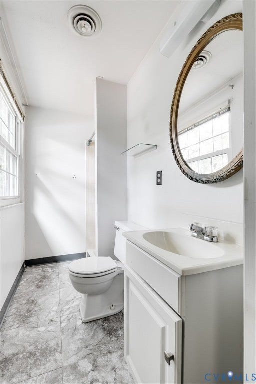 White vanity with an integrated sink and chrome faucet, set against a wall with a prominent decorative mirror