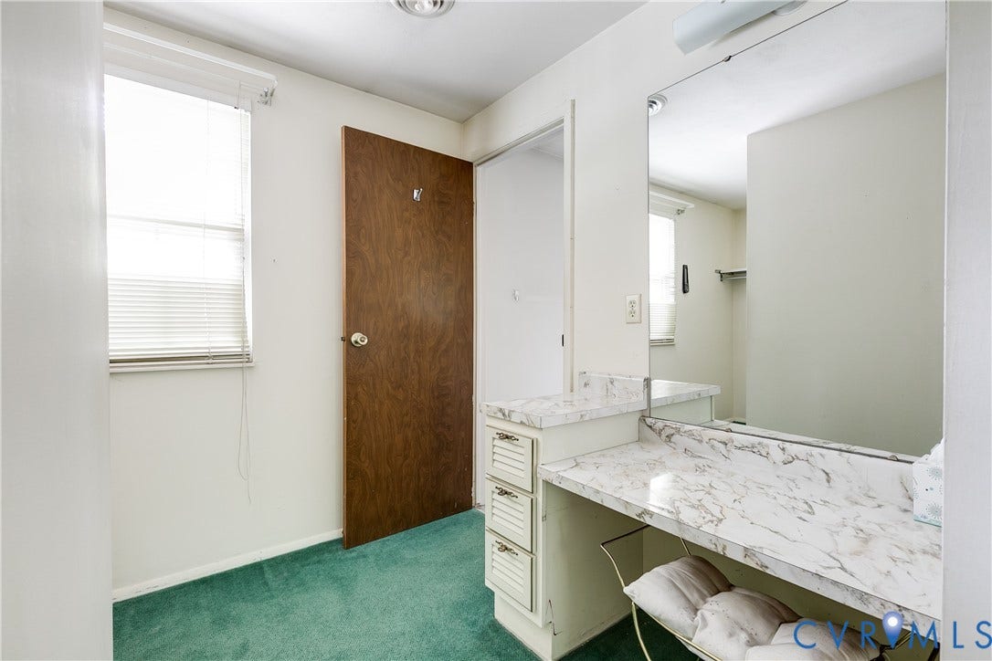 Built-in vanity with a large mirror, integrated storage drawers, and a window for natural light