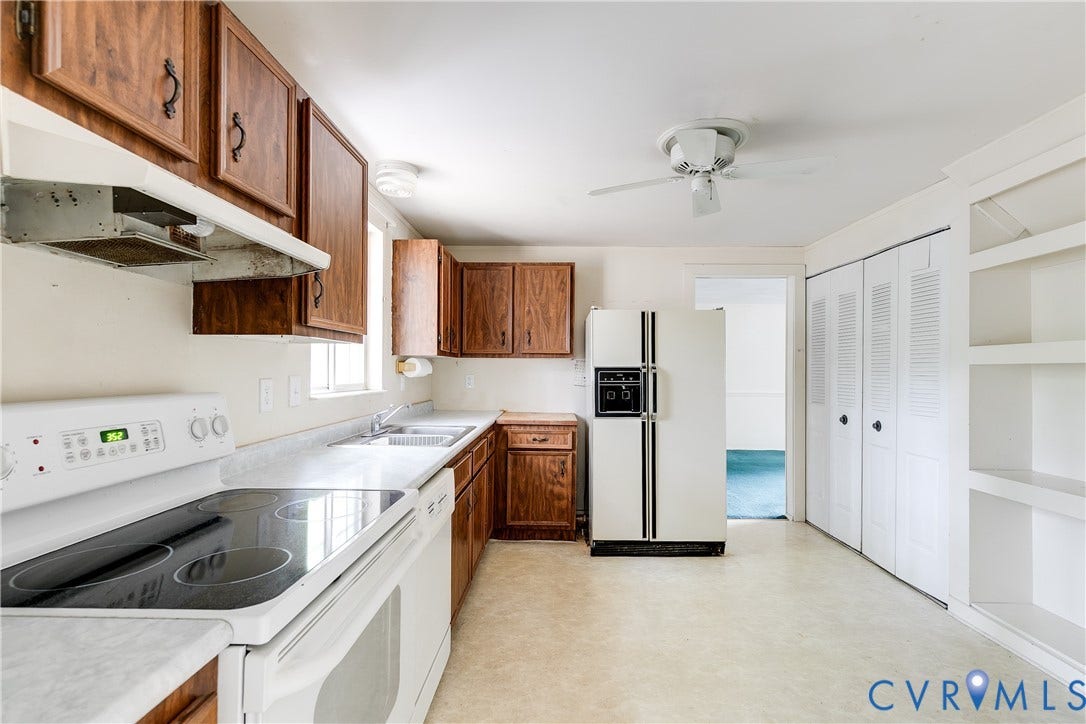 Kitchen featuring wood-finish cabinetry, white countertops, a double basin sink, and built-in shelving