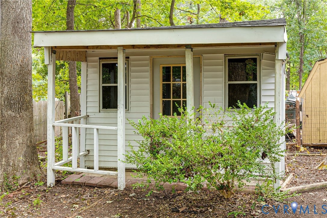 Detached storage shed with siding exterior, covered porch, and multiple windows