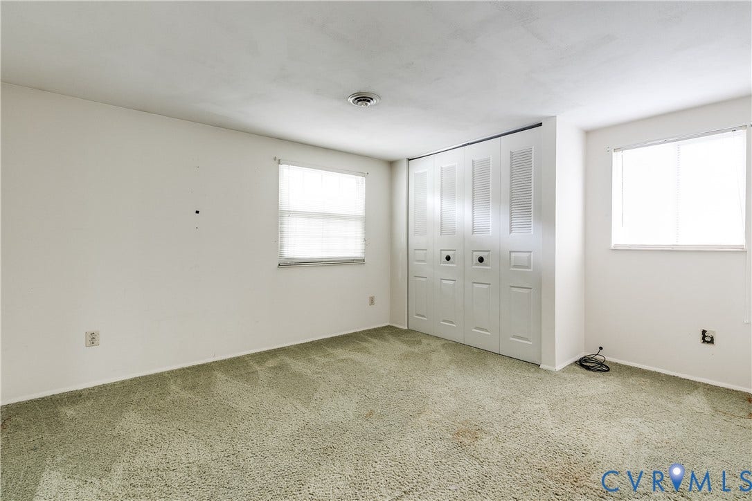 White walls and light green carpeting with two windows