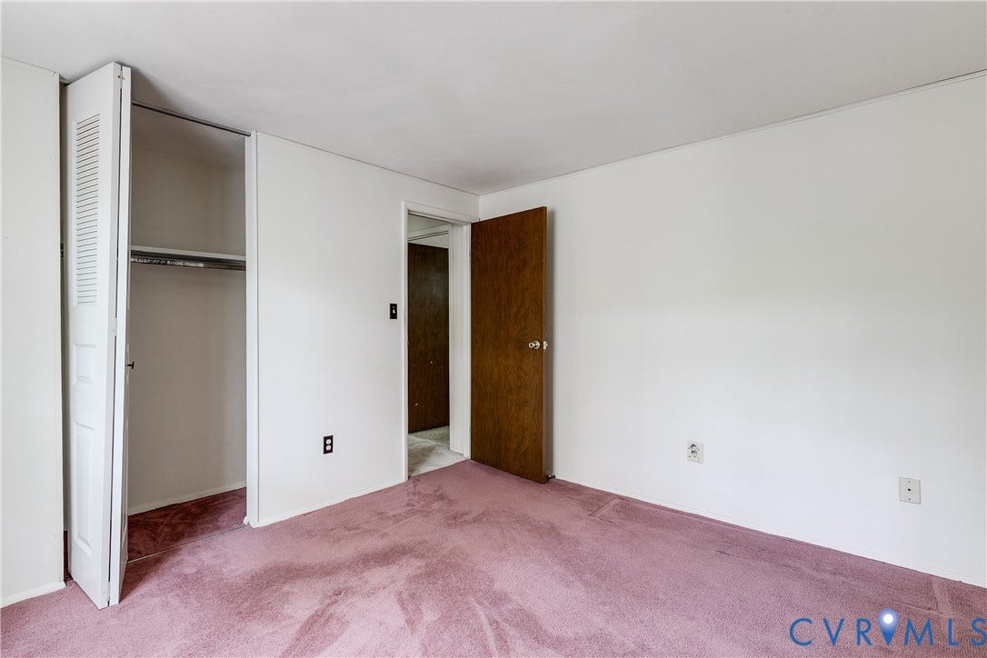 White walls with a textured ceiling, a closet featuring bi-fold louvered doors, and a wood-finish interior door