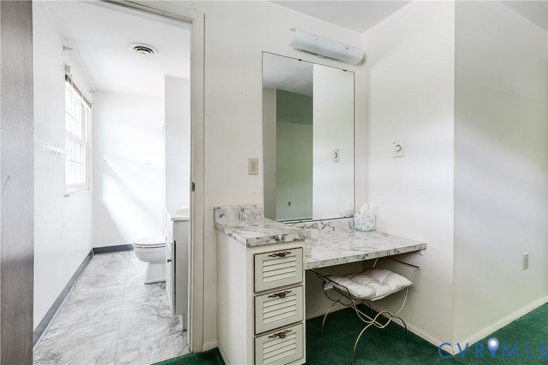 Integrated vanity with a stone-finish countertop, mirror, and dedicated lighting