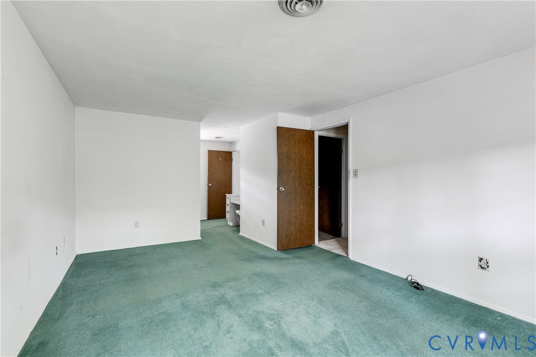Green carpeted flooring, white painted walls, and wood-panel doors