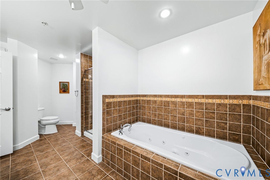 4820 Old Main Street, #503, Sky Line Condo, Richmond, VA 23231 Jetted soaking tub with tiled surround, walk-in shower with glass enclosure, white toilet, and recessed lighting
