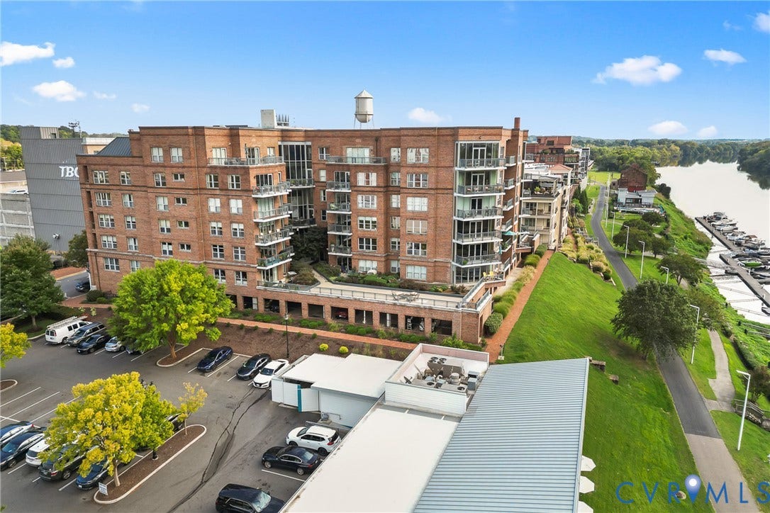 4820 Old Main Street, #503, Sky Line Condo, Richmond, VA 23231 Brick facade building featuring multiple balconies, a waterside location, an adjacent paved pathway, and a nearby marina