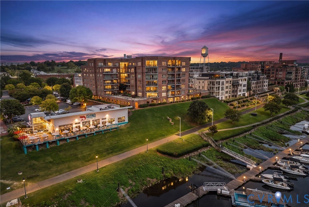4820 Old Main Street, #503, Sky Line Condo, Richmond, VA 23231 Multi-story residential buildings with balconies, waterfront access with docks, commercial storefronts, paved pathways, and a water tower in the background