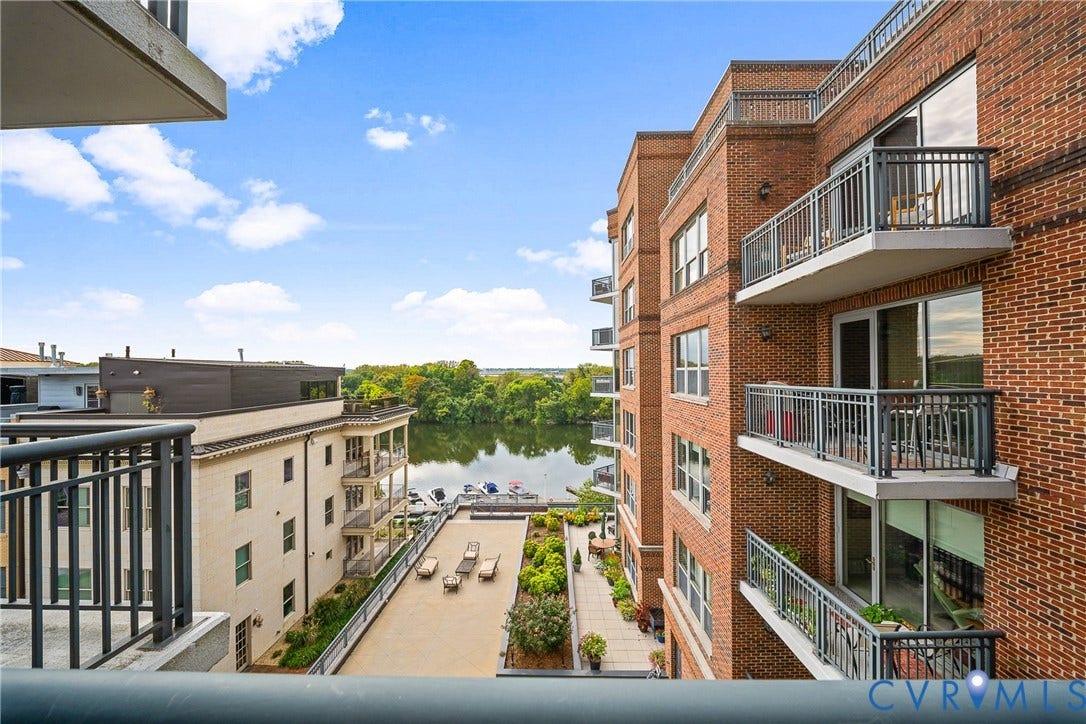 4820 Old Main Street, #503, Sky Line Condo, Richmond, VA 23231 Brick exterior building with multiple private balconies, a water body, and a structured outdoor patio space
