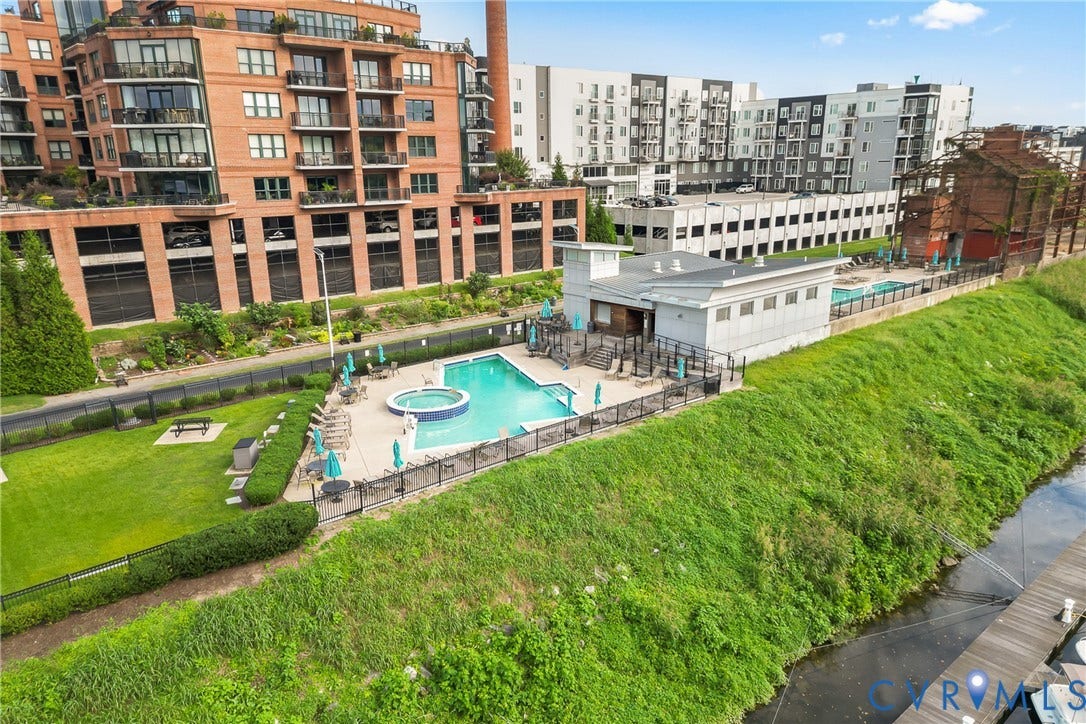 4820 Old Main Street, #503, Sky Line Condo, Richmond, VA 23231 Outdoor swimming pool with integrated spa, surrounding paved patio, manicured lawn, and adjacent multi-story residential buildings