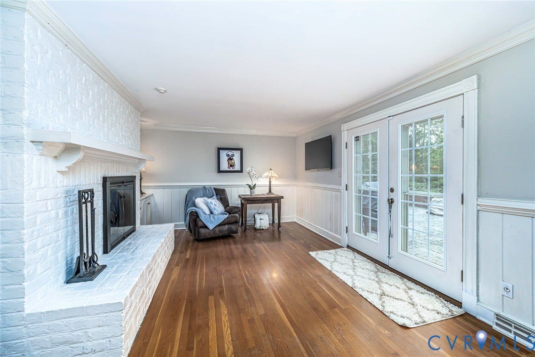 Hardwood flooring, painted brick fireplace with mantel, crown molding, wainscoting, and French doors
