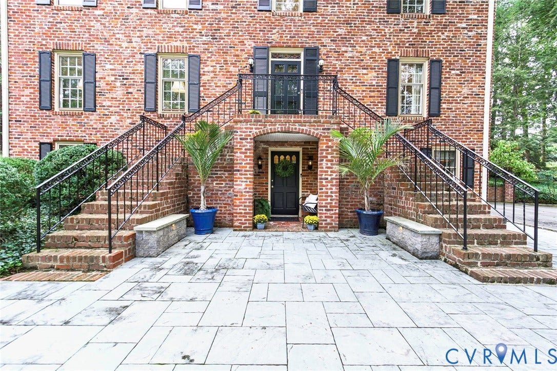 Brick facade with dark shutters and a central arched entry