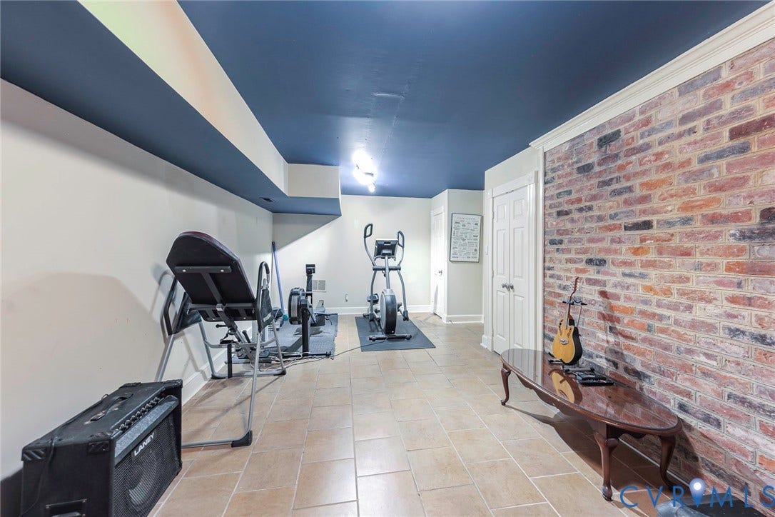 Exposed brick accent wall, tile flooring, crown molding, double paneled doors, and recessed ceiling lighting