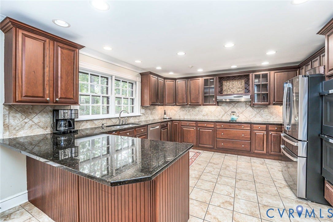 Kitchen featuring wood cabinetry, granite countertops, a tiled backsplash, and recessed lighting