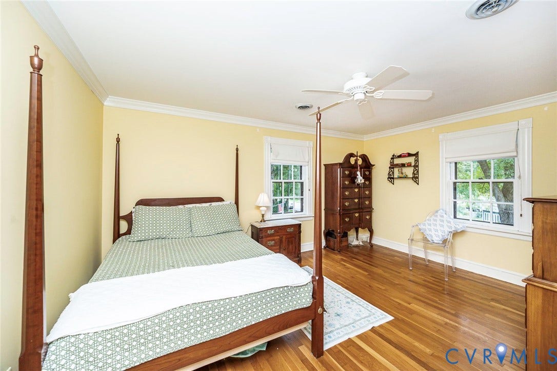 Hardwood flooring, crown molding, two windows with white trim, white ceiling fan, and light yellow wall color
