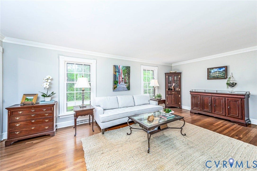 Hardwood flooring throughout, white crown molding, light gray wall paint, and white trim windows