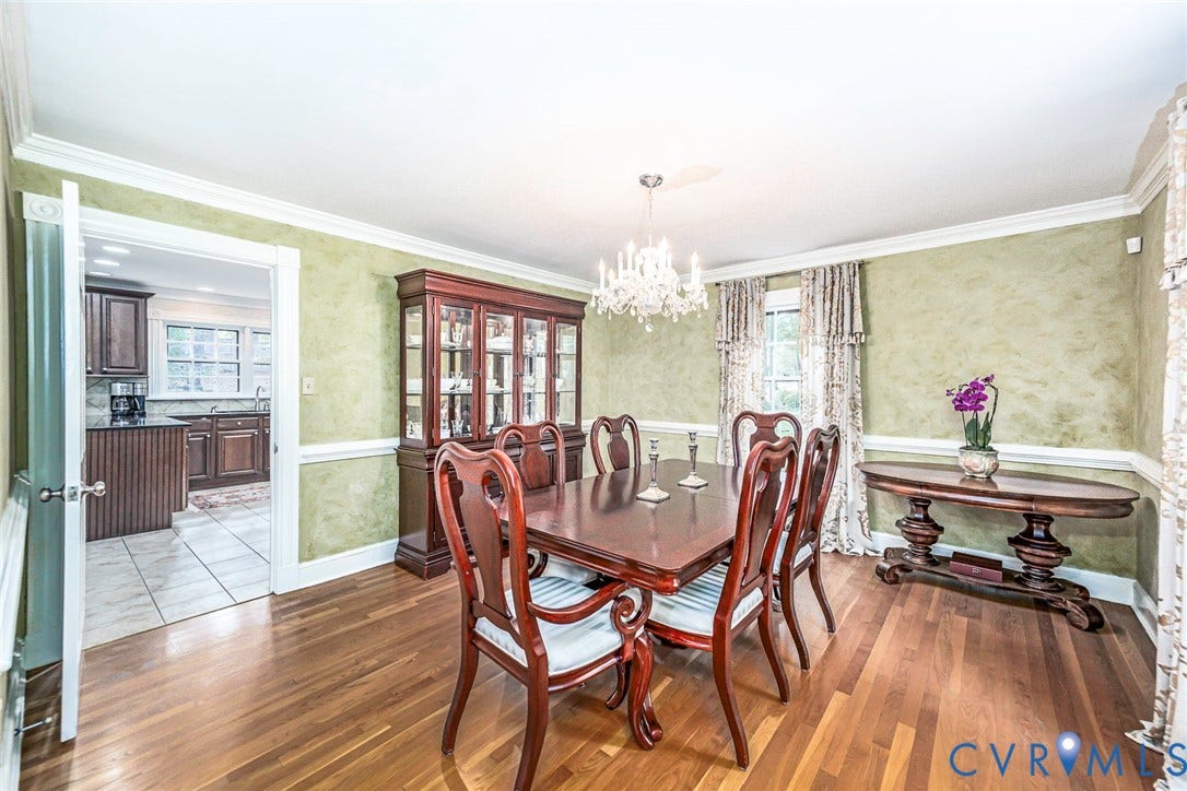 Hardwood flooring, decorative wall treatment, white crown molding, white chair rail, and a crystal chandelier