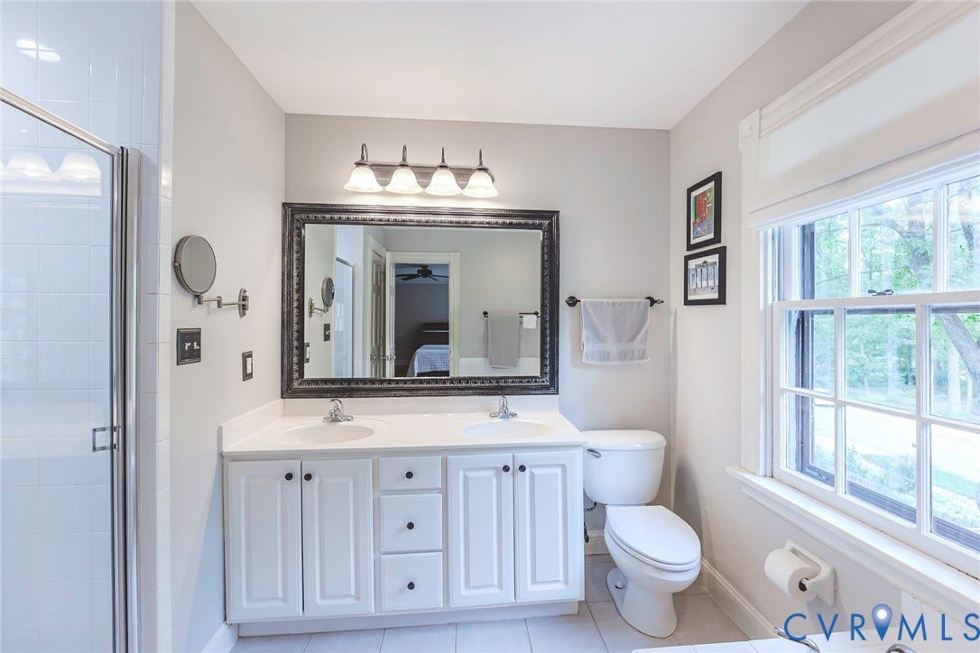 Dual vanity with white cabinetry, framed mirror, and integrated lighting