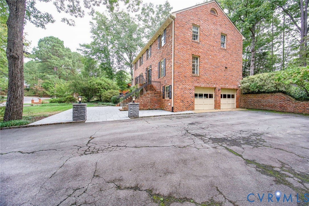 Brick exterior construction featuring shuttered windows, a two-car garage, and a brick retaining wall