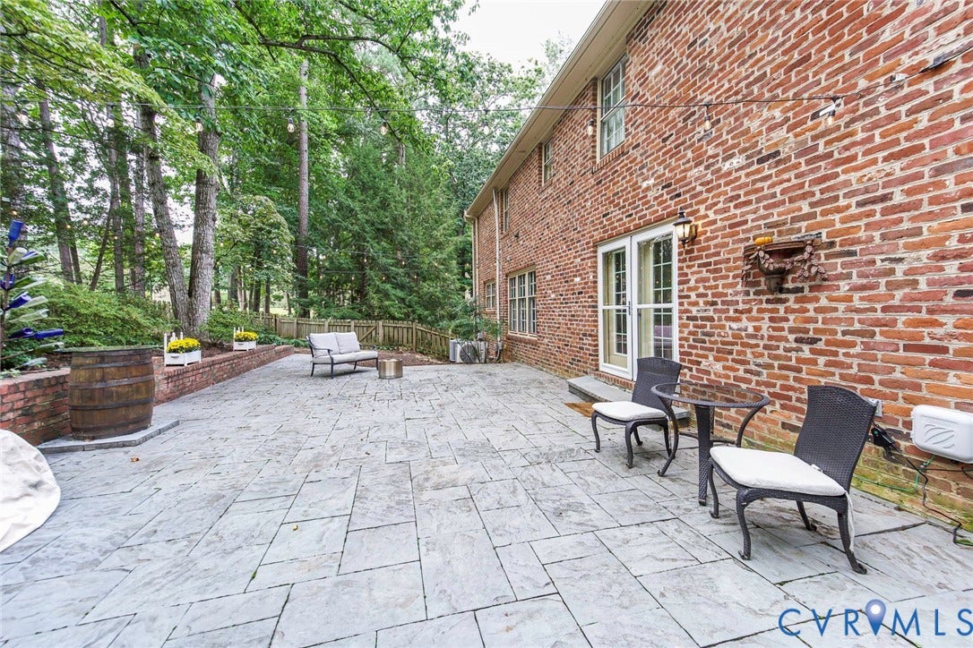 Expansive patio with pavers;  brick retaining wall and mature trees