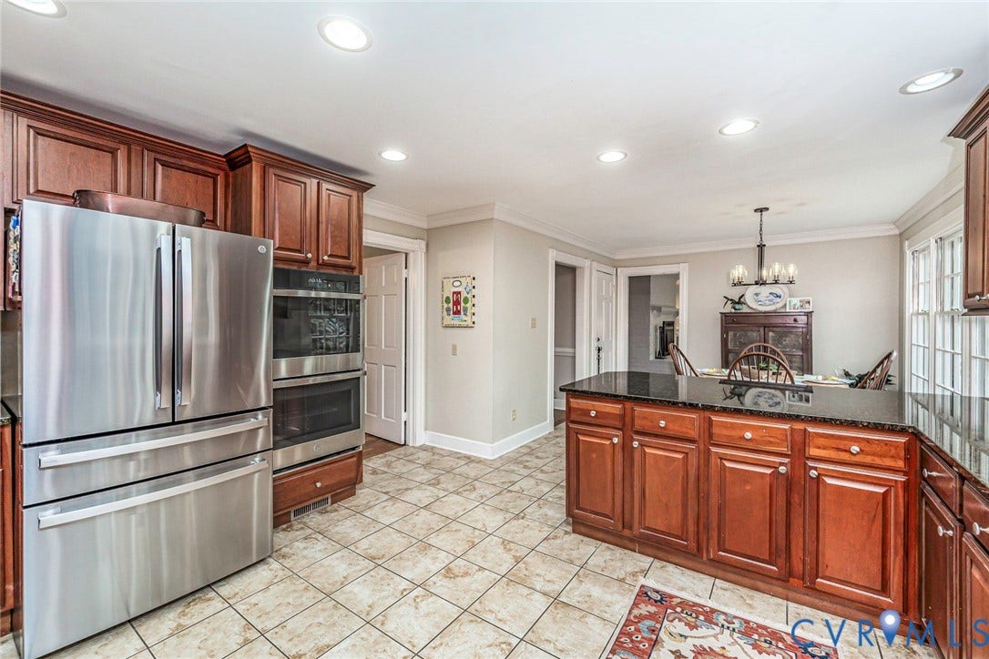 Kitchen featuring wood cabinetry, stainless steel appliances, a center island with a granite countertop, and recessed lighting