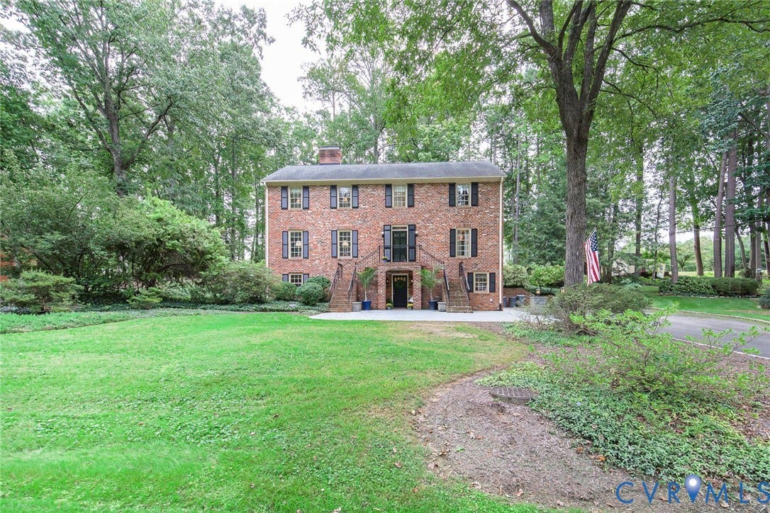 Brick Colonial exterior with a symmetrical facade, multiple windows, and a prominent front entrance featuring dual staircases