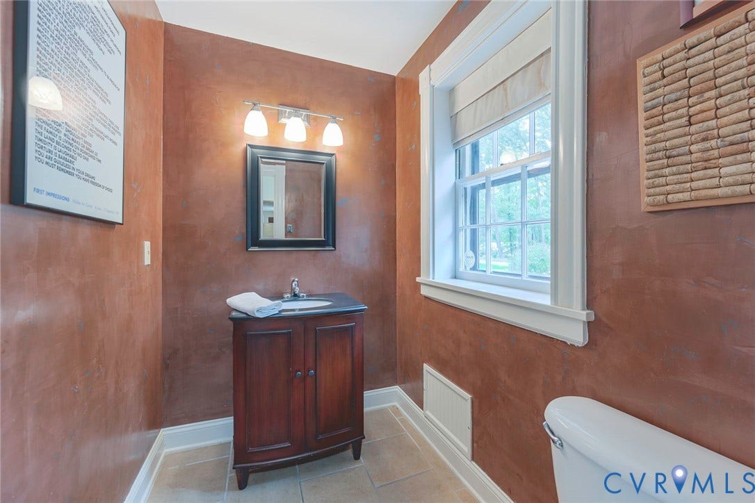 Wood-finish vanity with an integrated sink, framed mirror, and a three-light vanity fixture