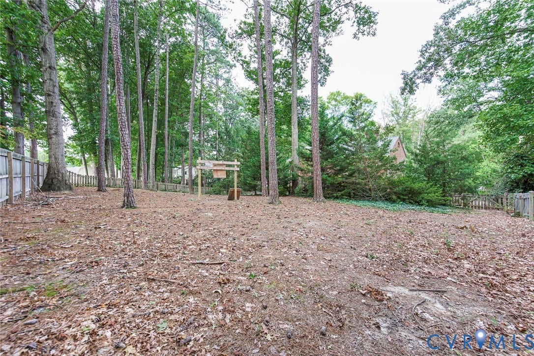 Expansive natural landscape featuring mature trees and perimeter fencing