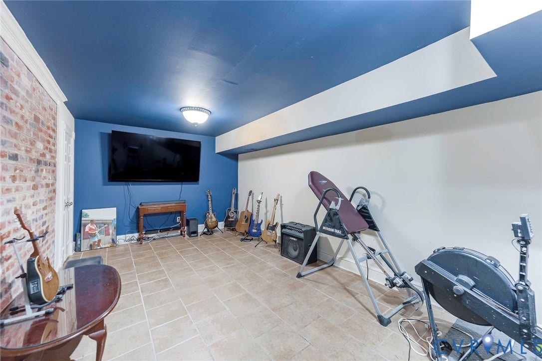 Exposed brick accent wall, tiled flooring, mounted ceiling light fixture, and blue painted ceiling