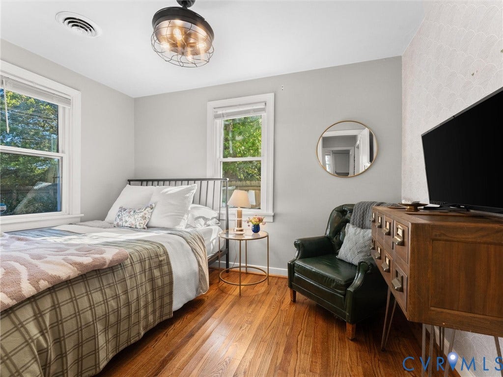 3933 Alma Avenue, Richmond, VA 23222 Hardwood flooring, two windows, ceiling fan with integrated lighting, built-in shelving, and accent wall with patterned wallpaper