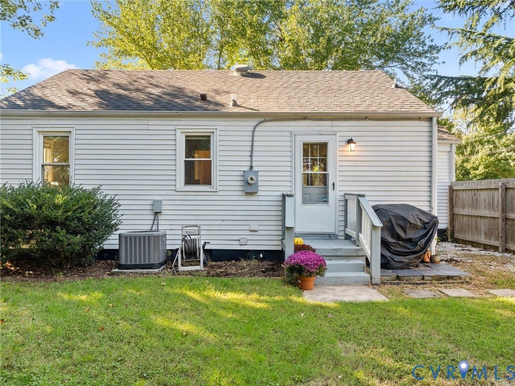 3933 Alma Avenue, Richmond, VA 23222 White horizontal siding with a shingled roof, a back door with an exterior light, and a wooden fence