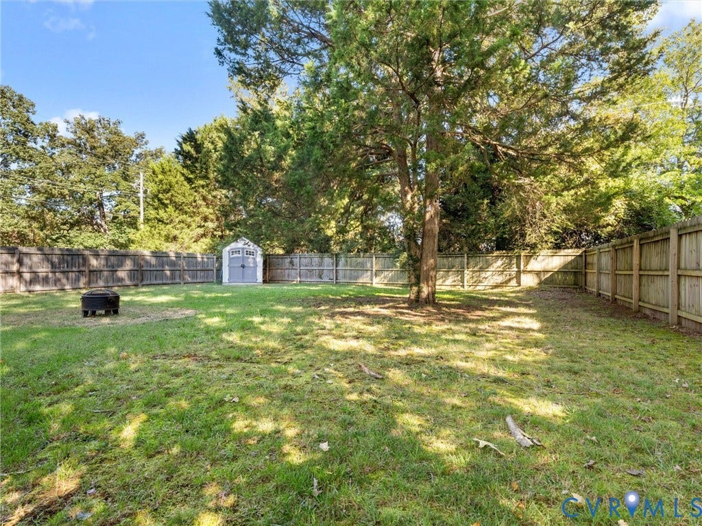 3933 Alma Avenue, Richmond, VA 23222 Expansive backyard with a manicured lawn, established mature trees, a wooden privacy fence, and a utility shed