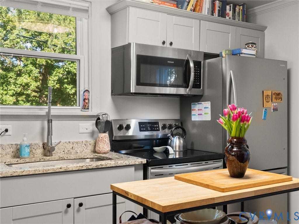 3933 Alma Avenue, Richmond, VA 23222 Light gray cabinetry, stainless steel appliances, granite-style countertops, wood-finish portable island, and a window with natural light