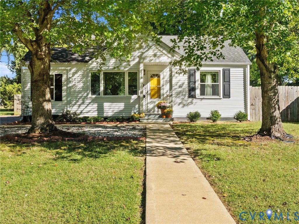 3933 Alma Avenue, Richmond, VA 23222 White siding exterior with a bright yellow front door, a concrete pathway, a wooden privacy fence, and mature trees