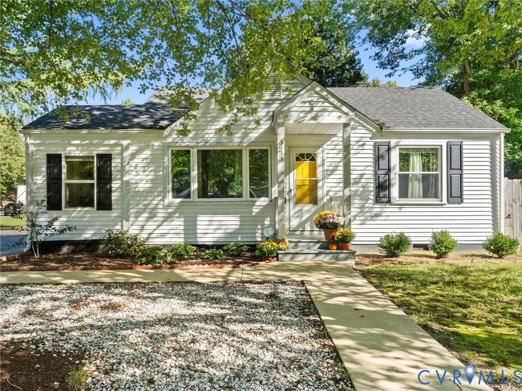 3933 Alma Avenue, Richmond, VA 23222 White siding exterior with dark shutters, prominent front entry with a yellow door, gray shingle roof, and a concrete walkway
