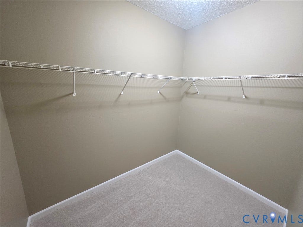 Built-in wire shelving system, light neutral wall paint, and light-toned carpet flooring