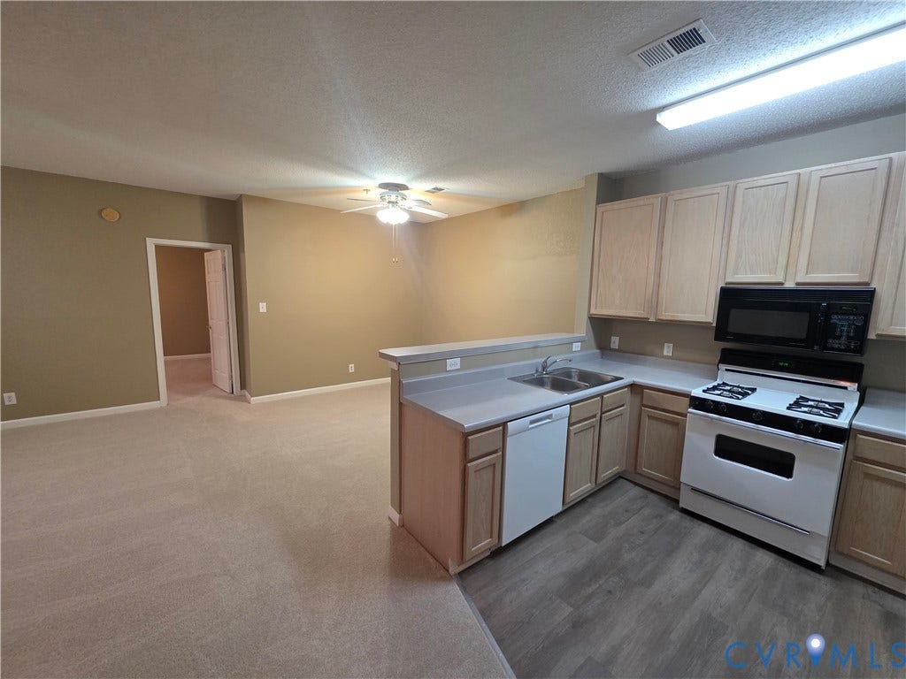 Kitchen with wood-finish cabinetry, stainless steel sink, gas range, and wood-finish flooring