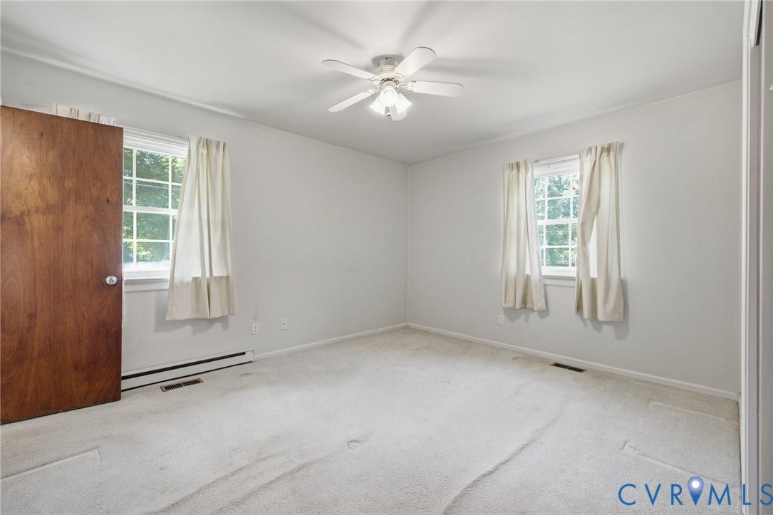 10215 River Road, South Chesterfield, VA 23803 Carpeted flooring, white walls, two windows with white trim, and a ceiling fan