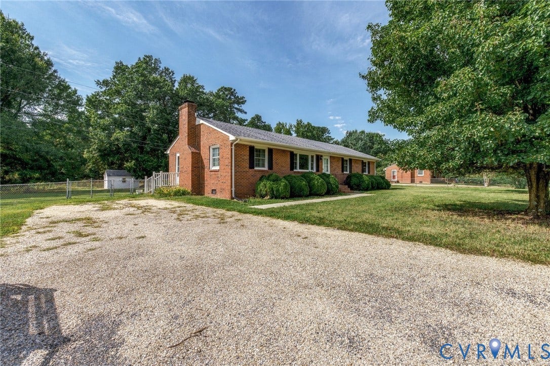 10215 River Road, South Chesterfield, VA 23803 Brick ranch-style home featuring a prominent chimney, dark window shutters, and established perimeter shrubbery