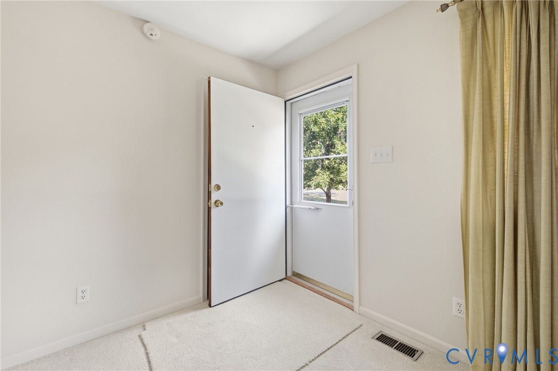 10215 River Road, South Chesterfield, VA 23803 Entry door with brass hardware and a storm door, light wall paint, and light-toned carpeting