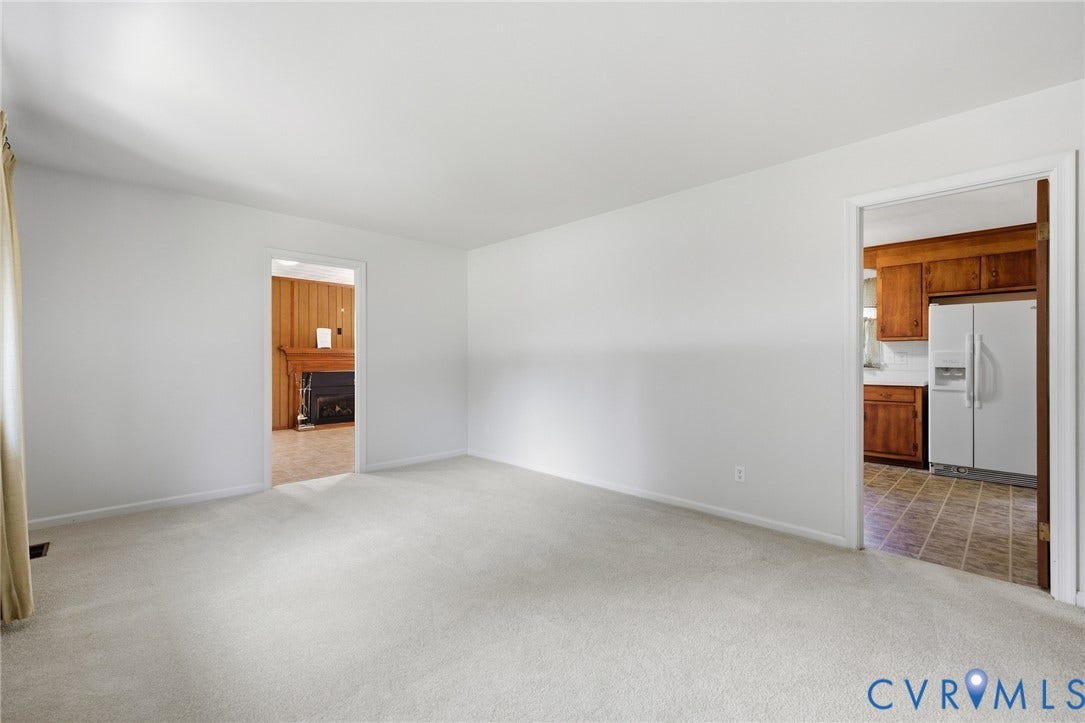 10215 River Road, South Chesterfield, VA 23803 Neutral-toned carpeted flooring throughout, with a clear passage to a room featuring wood paneling and a fireplace