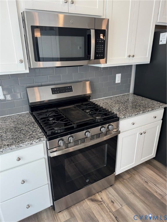 16025 Abelson Way, Chesterfield, VA 23832 Stainless steel microwave and gas range, white shaker-style cabinetry, granite countertops, gray subway tile backsplash, and wood-finish flooring.