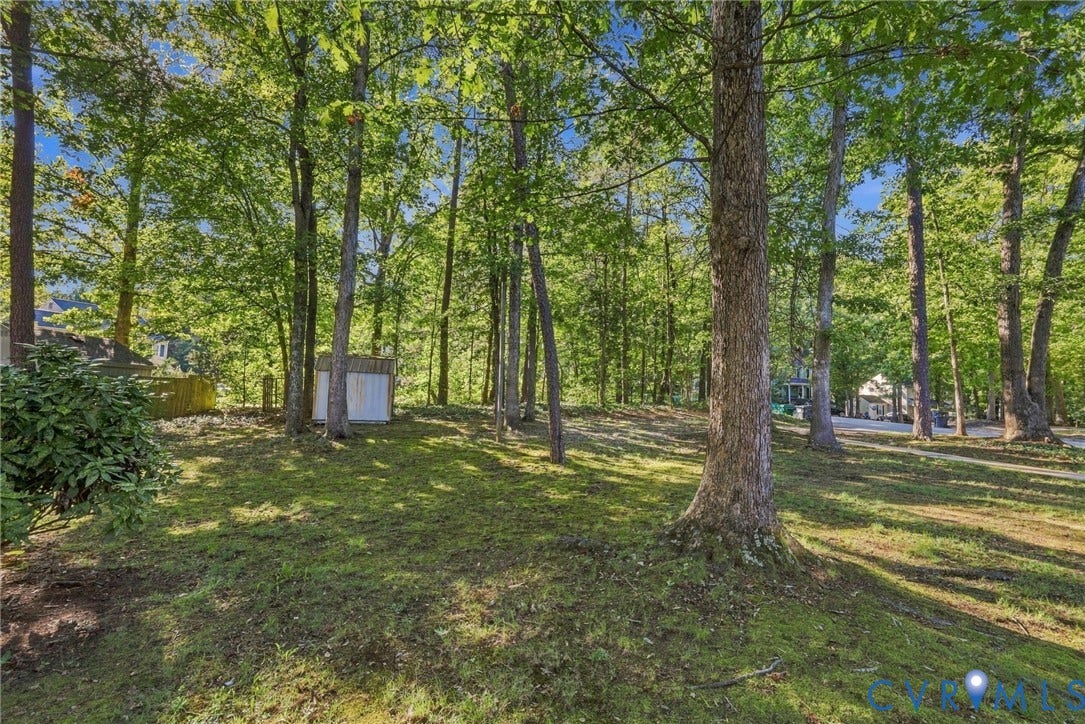 12308 Poplar Forest Drive, Tuckahoe Village, Henrico, VA 23238 Wooded lot featuring mature trees, a gently sloped grassy area, and a storage shed