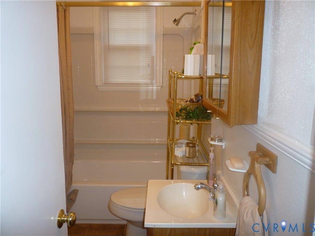1645 Manakin Road, Manakin, VA 23103 White shower-over-tub combination with a wall-mounted showerhead and gold-toned shower rod
