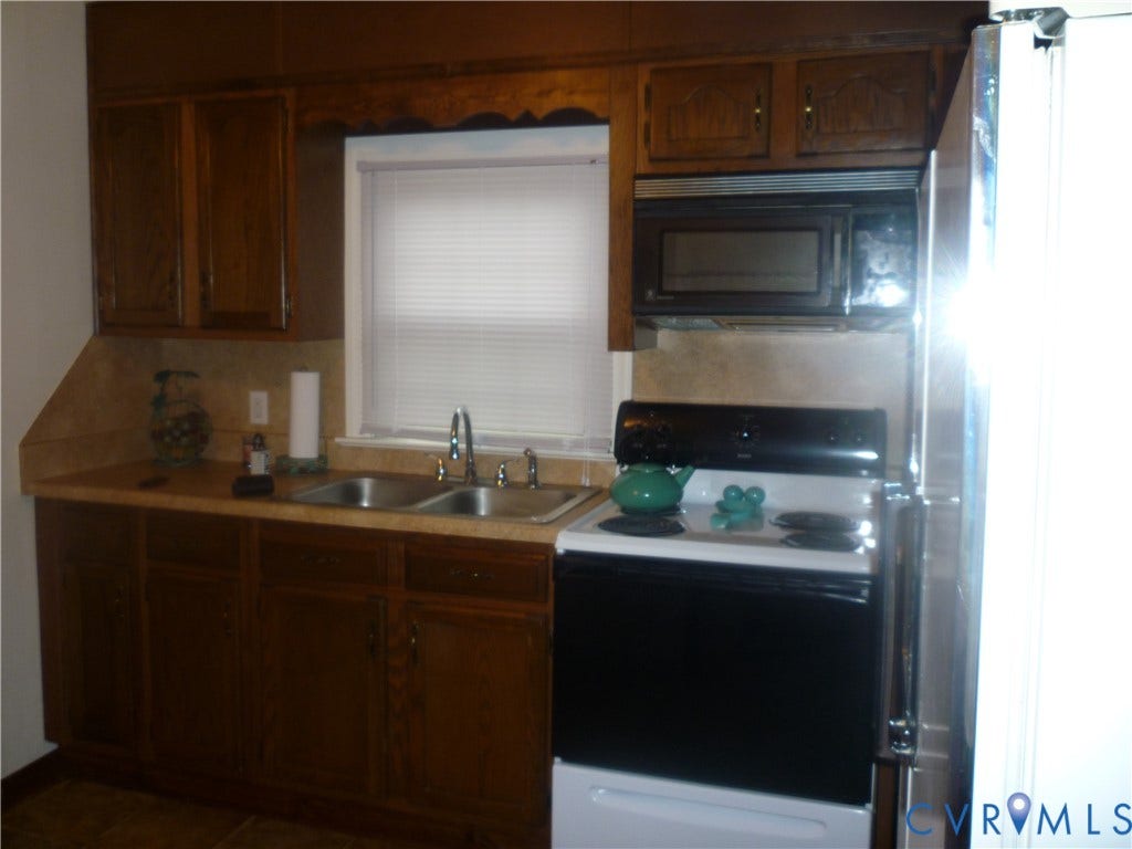 1645 Manakin Road, Manakin, VA 23103 Wood-finish cabinetry, double basin sink, neutral countertops, over-the-range microwave, and a black and white electric range