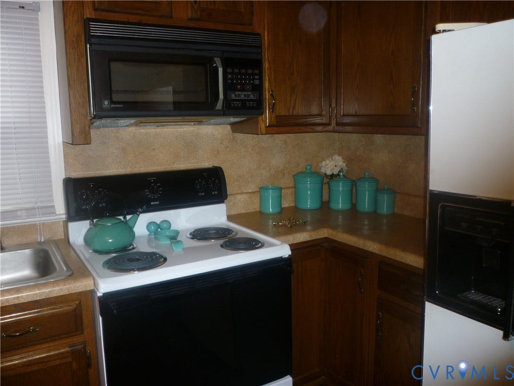 1645 Manakin Road, Manakin, VA 23103 Built-in microwave, wood cabinetry, laminate countertops, stainless steel sink, and white freestanding range