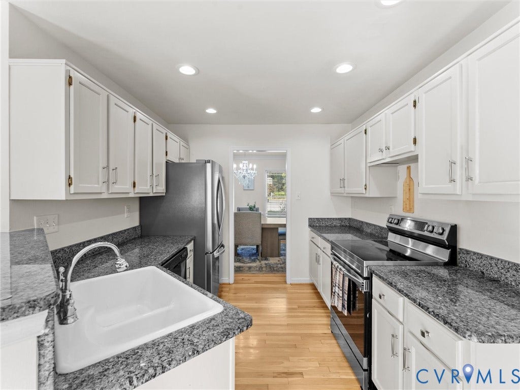 White cabinetry with modern hardware, stainless steel appliances, granite countertops, single basin sink with chrome faucet, and wood-finish flooring