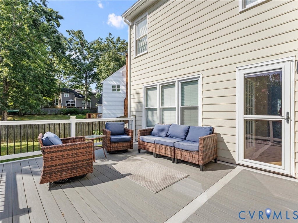 Expansive rear deck featuring composite decking, white railing with black balusters, and a glass-paneled door