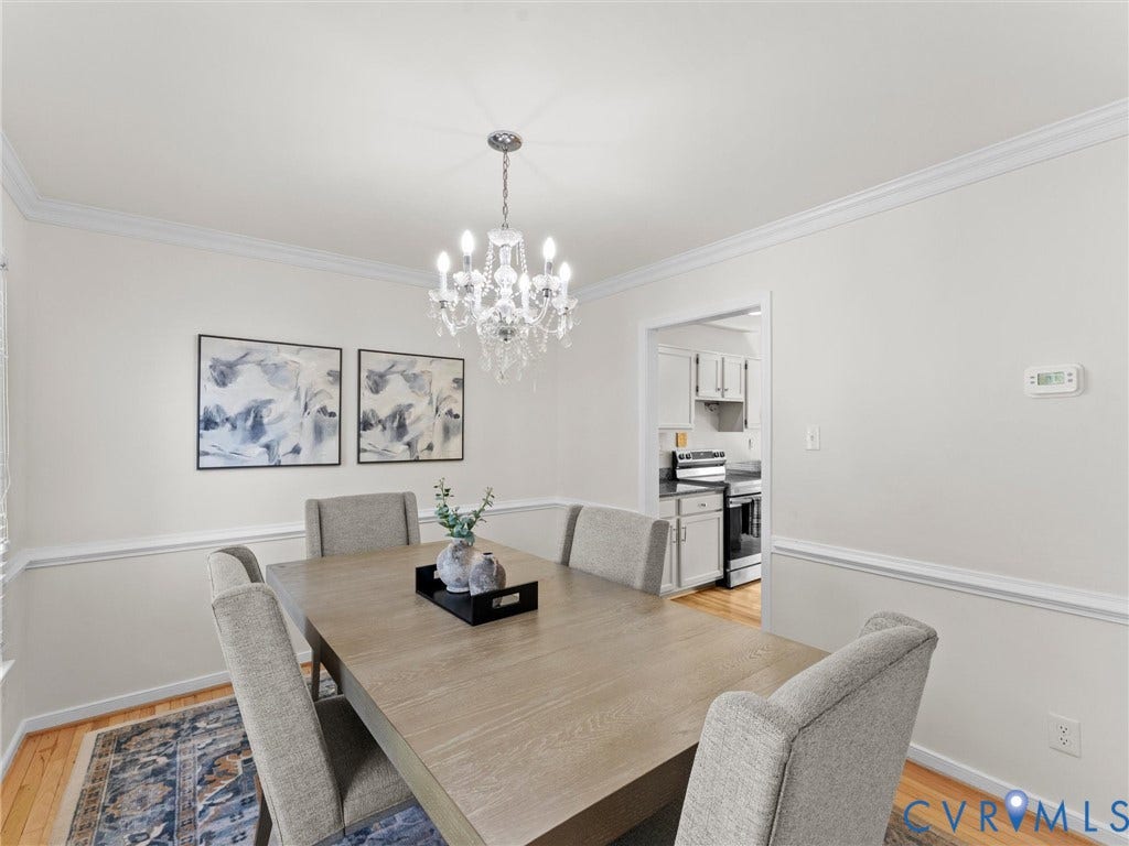 Crown molding, chair rail molding, chandelier lighting, hardwood flooring, and a cased opening