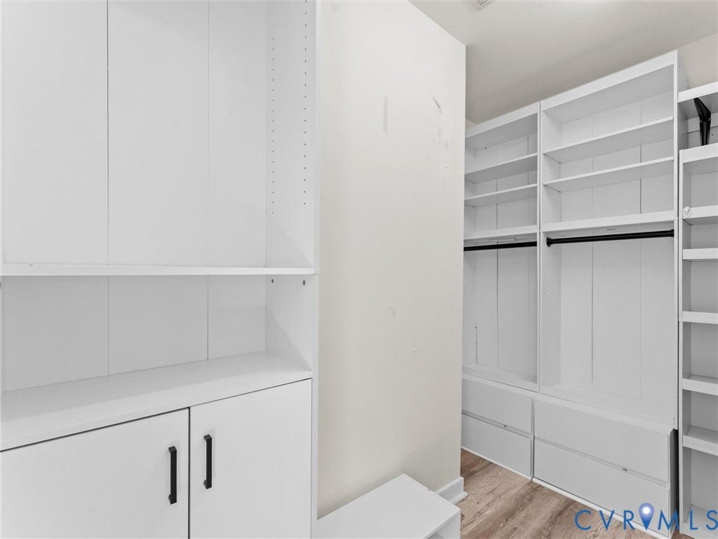White built-in cabinetry with shelving and drawers, complemented by wood-finish flooring