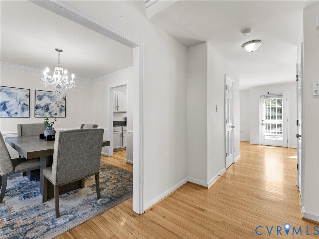 Hardwood flooring throughout, with a crystal chandelier, crown molding, and a white paneled door with glass inserts
